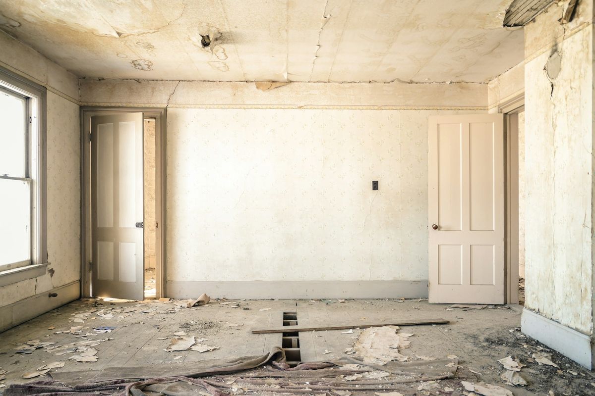 Lege oude kamer met afbladderend behang en een beschadigde vloer