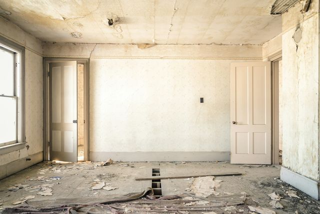 Lege oude kamer met afbladderend behang en een beschadigde vloer